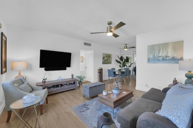 living room with wood finished floors, a ceiling fan, and visible vents