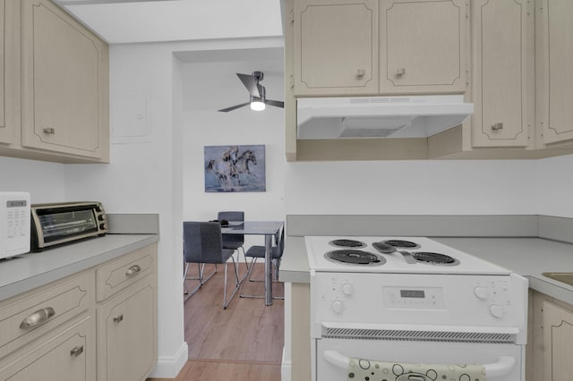 kitchen featuring under cabinet range hood, white appliances, light wood-style floors, and light countertops