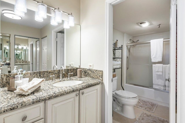 bathroom with vanity, visible vents, bath / shower combo with glass door, tile patterned floors, and toilet