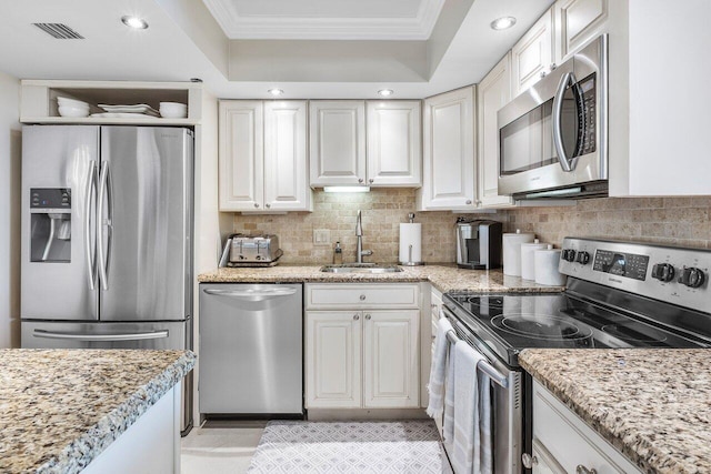 kitchen featuring white cabinetry, ornamental molding, appliances with stainless steel finishes, and a sink