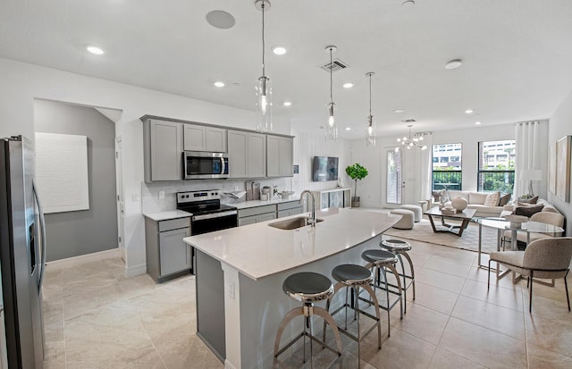 kitchen featuring visible vents, a sink, gray cabinetry, stainless steel appliances, and open floor plan