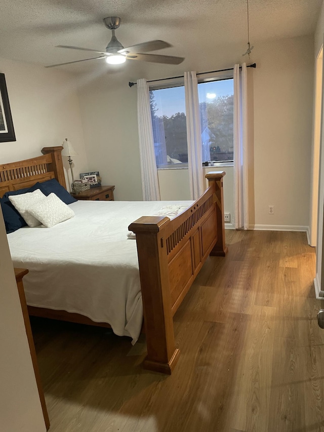 bedroom featuring ceiling fan, wood finished floors, baseboards, and a textured ceiling