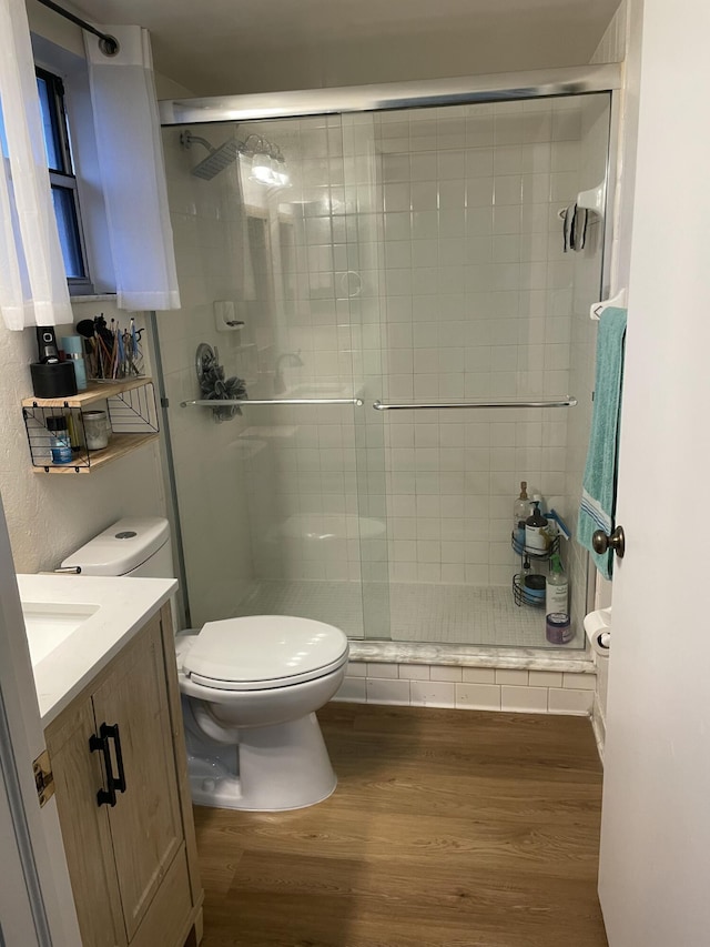 full bath featuring a stall shower, toilet, vanity, and wood finished floors