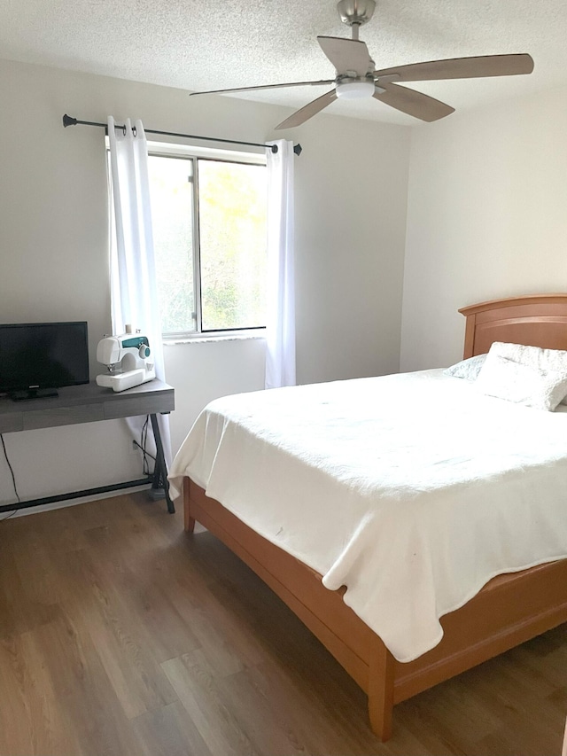 bedroom with ceiling fan, a textured ceiling, and wood finished floors