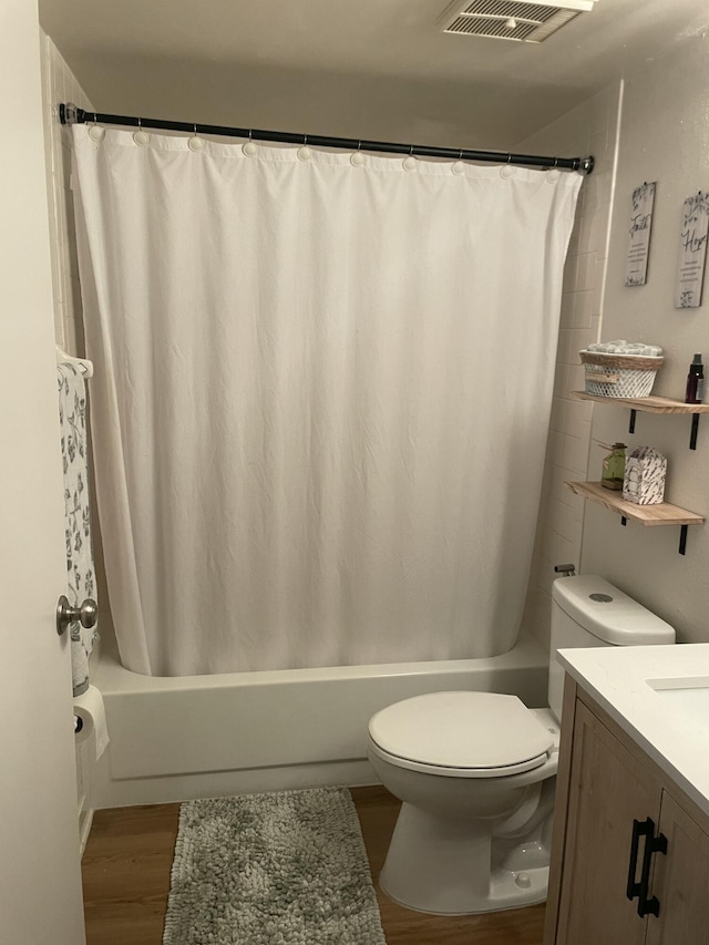 full bath with visible vents, toilet, wood finished floors, vanity, and shower / bathtub combination with curtain