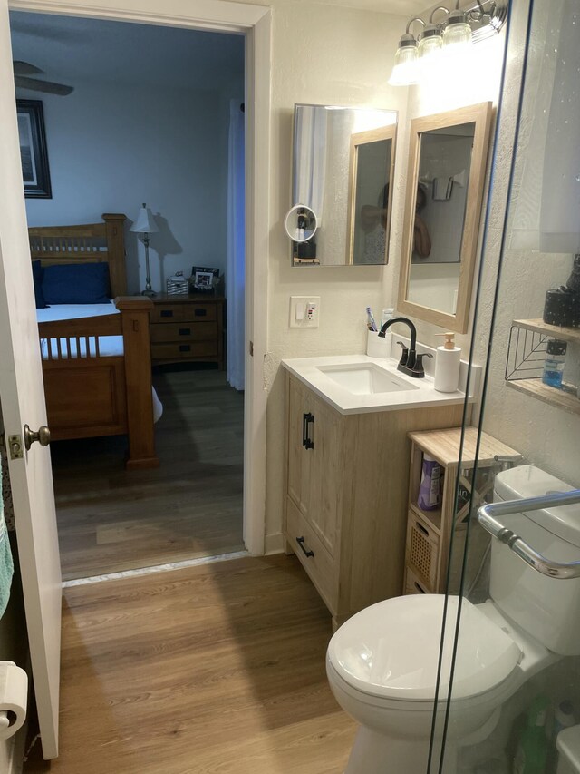 bathroom with toilet, wood finished floors, and vanity