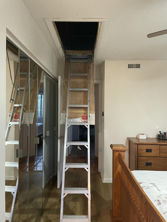 stairway featuring a ceiling fan, wood finished floors, visible vents, and a textured ceiling