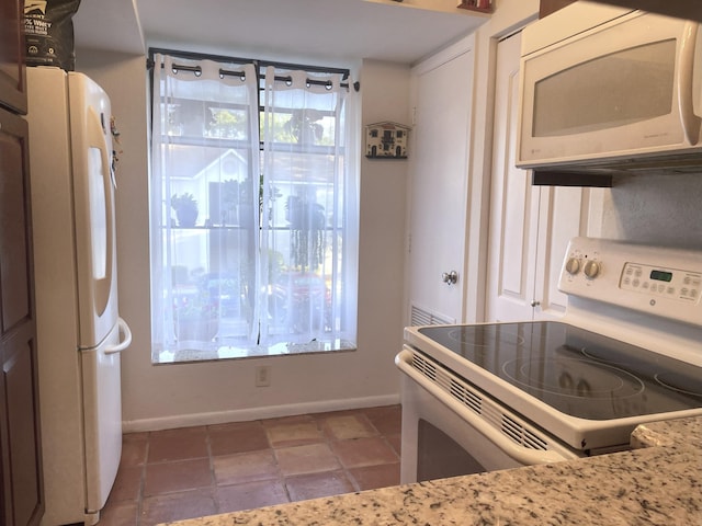 kitchen featuring baseboards, white appliances, and tile patterned flooring