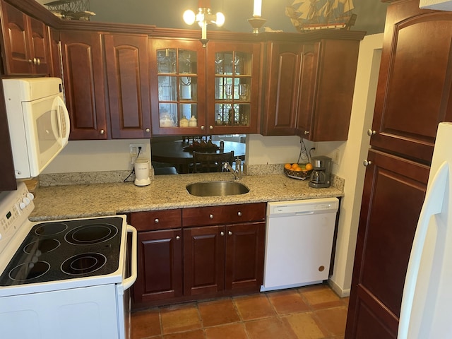 kitchen featuring a sink, glass insert cabinets, white appliances, and light stone countertops