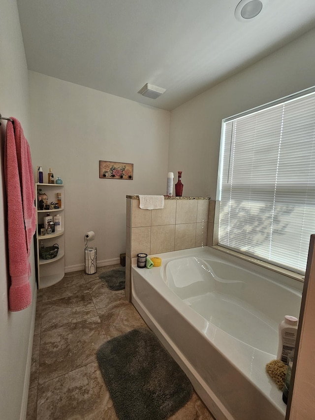 bathroom featuring visible vents, baseboards, and a garden tub