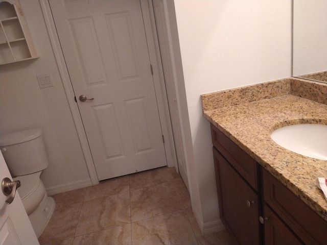 bathroom with vanity, toilet, baseboards, and tile patterned flooring