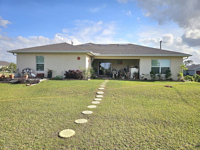 back of house with stucco siding, a yard, a shingled roof, and a patio area