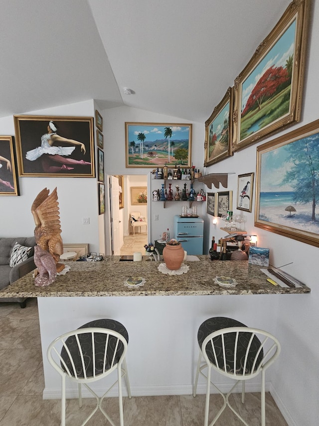 kitchen with stone counters, tile patterned floors, and vaulted ceiling