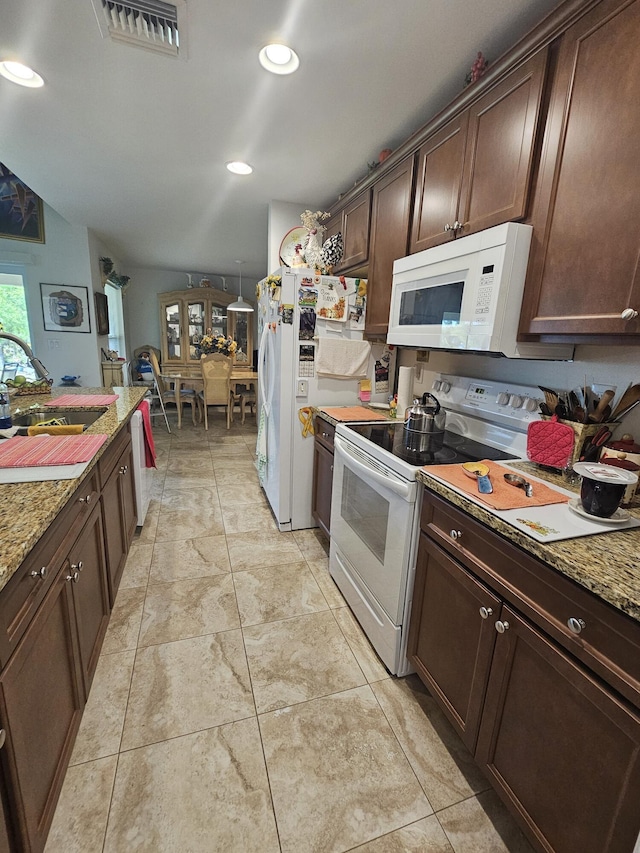 kitchen with visible vents, a sink, white appliances, light stone countertops, and dark brown cabinets