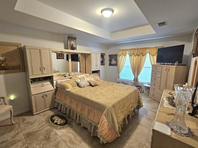 bedroom with a raised ceiling, baseboards, and visible vents