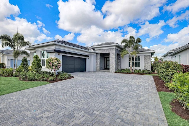 view of front of house featuring decorative driveway, a garage, and stucco siding