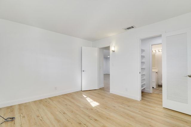 unfurnished bedroom featuring light wood finished floors, baseboards, and a spacious closet