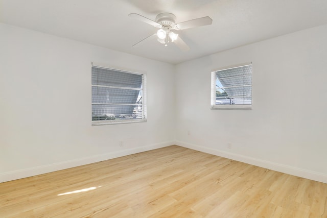 spare room with baseboards, light wood-style flooring, and a ceiling fan