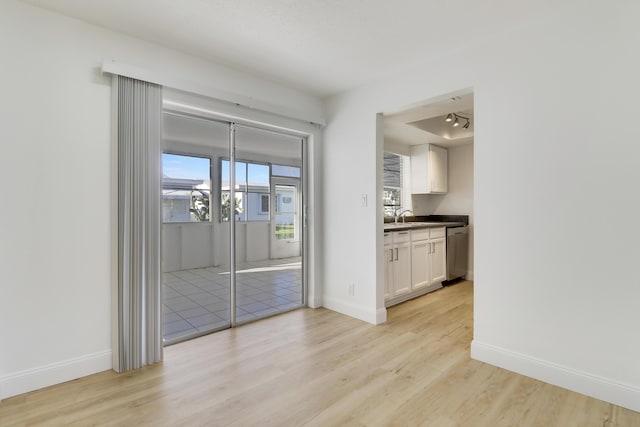 unfurnished dining area featuring a sink, light wood-style floors, and baseboards