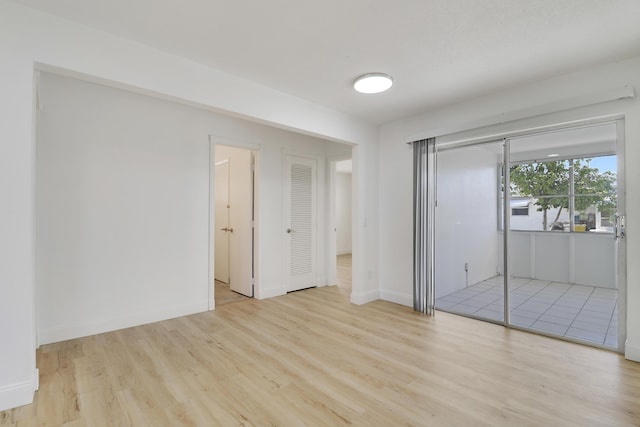 unfurnished bedroom with light wood-style floors, access to exterior, and baseboards
