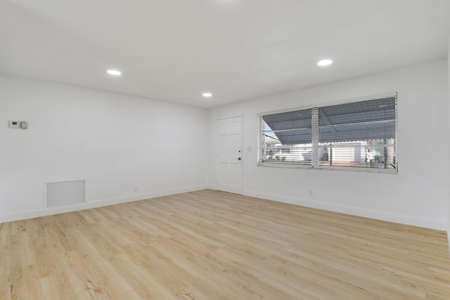 empty room featuring light wood-style flooring, baseboards, and visible vents