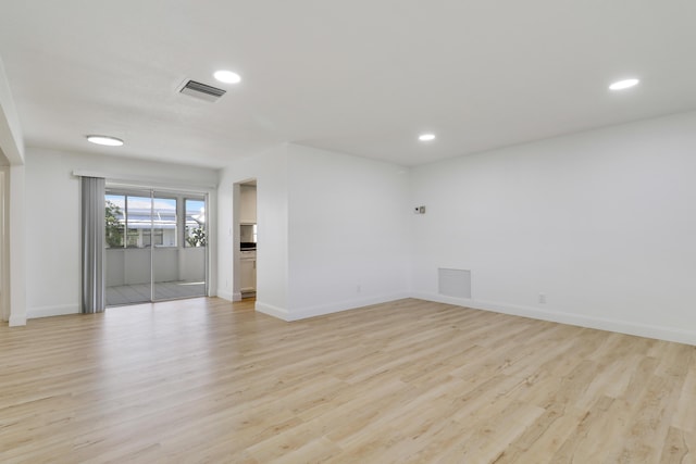 unfurnished room with light wood finished floors, visible vents, and baseboards