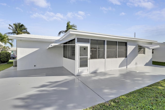 view of front of property featuring a patio, stucco siding, a sunroom, and central AC unit
