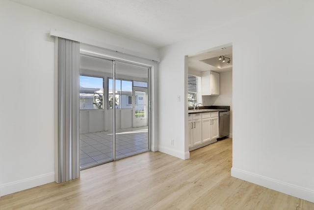 unfurnished dining area with light wood finished floors, a healthy amount of sunlight, and baseboards