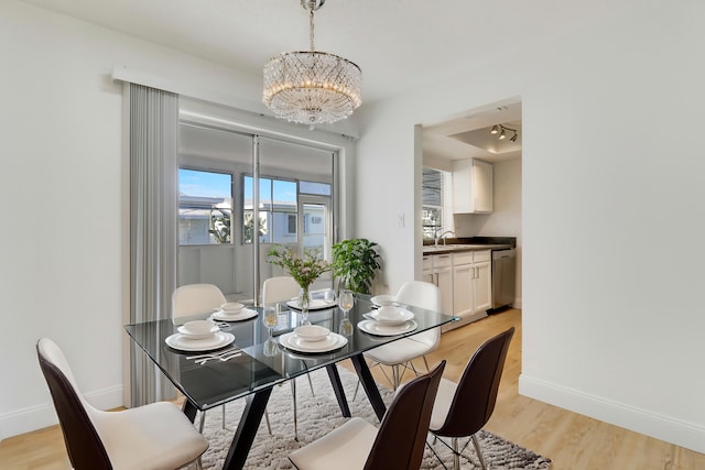 dining area featuring baseboards, light wood finished floors, and a chandelier