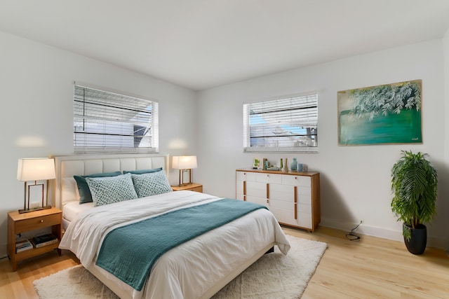 bedroom with multiple windows, wood finished floors, and baseboards