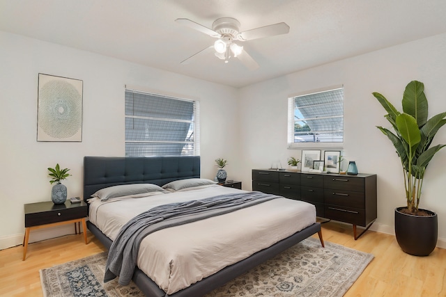 bedroom featuring a ceiling fan, baseboards, and light wood finished floors