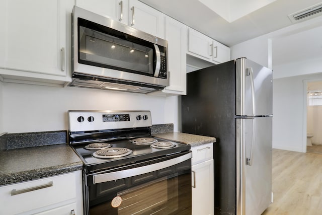 kitchen with stainless steel appliances, white cabinetry, light wood finished floors, and dark countertops