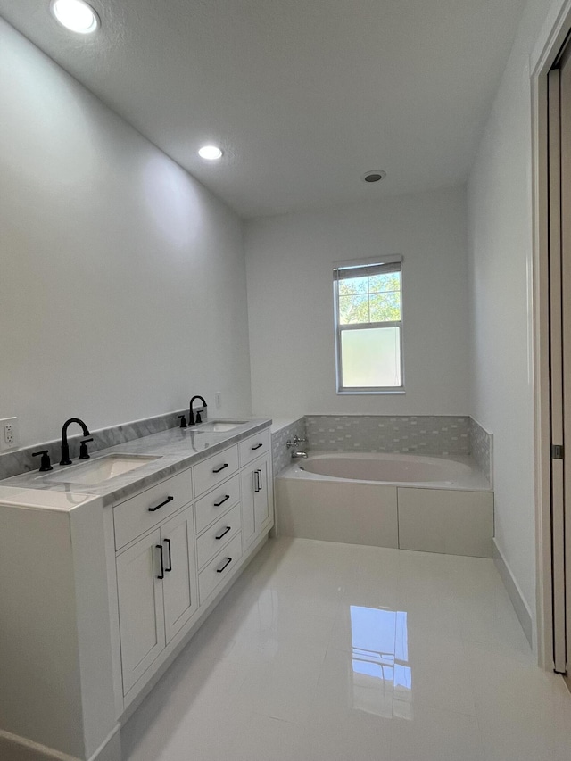 full bath featuring a garden tub, recessed lighting, tile patterned floors, and a sink