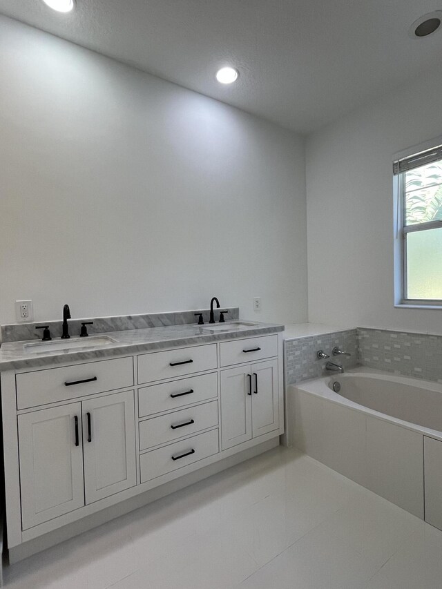 full bathroom with double vanity, a bath, recessed lighting, and a sink