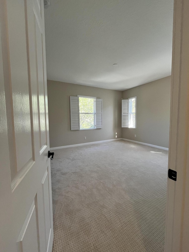 carpeted spare room featuring baseboards