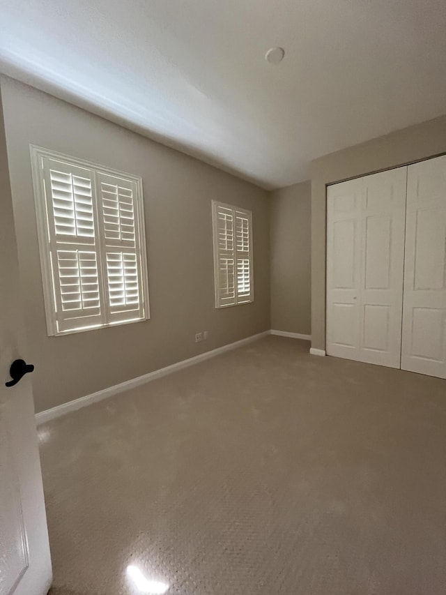 unfurnished bedroom with carpet flooring, baseboards, and a closet