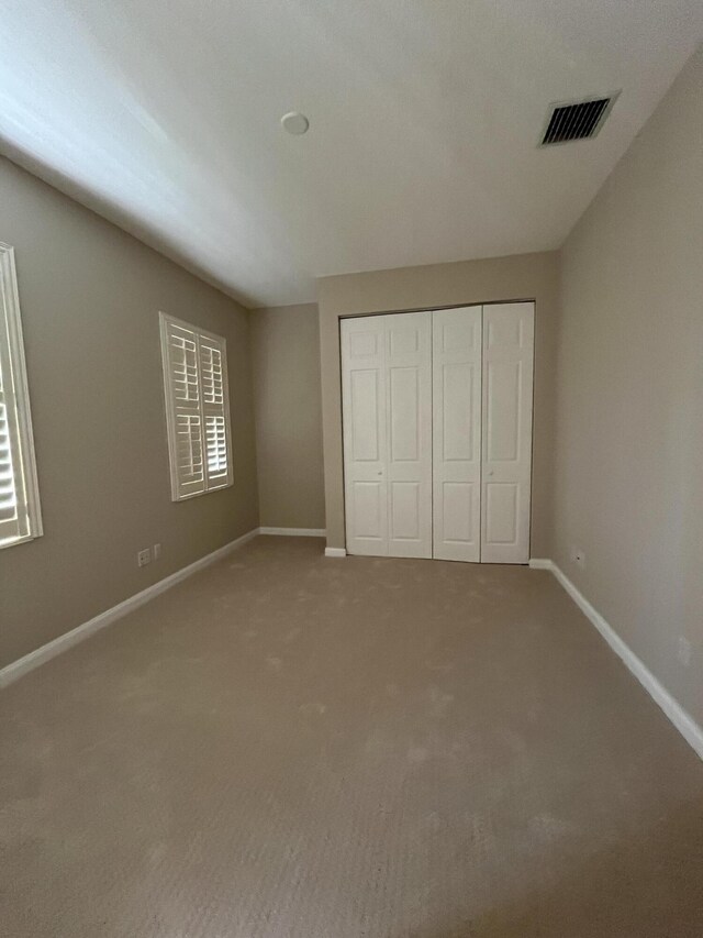 unfurnished bedroom featuring baseboards, visible vents, a closet, and carpet floors