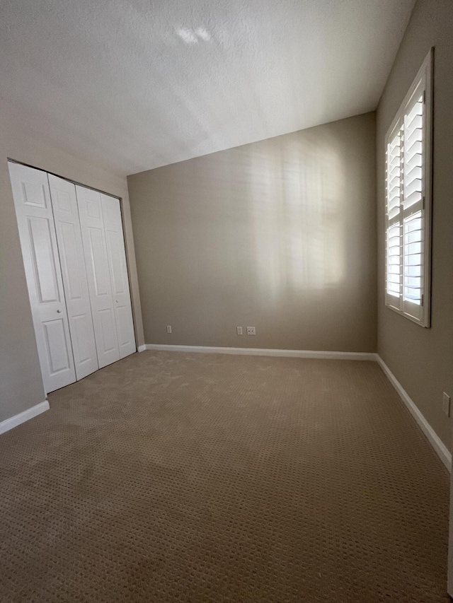 unfurnished bedroom featuring a closet, baseboards, carpet floors, and a textured ceiling