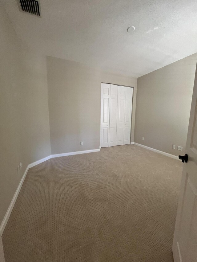 unfurnished bedroom with carpet flooring, baseboards, visible vents, and a closet