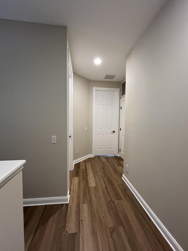 hallway with visible vents, baseboards, and wood finished floors