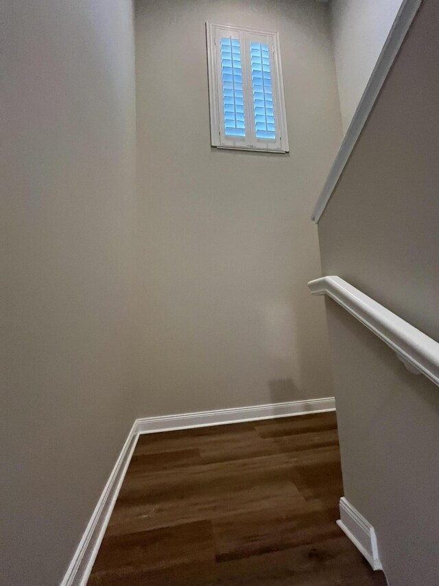 staircase featuring wood finished floors and baseboards