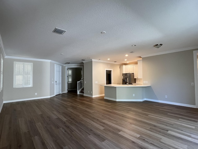 kitchen with black fridge, open floor plan, a peninsula, light countertops, and dark wood-style flooring