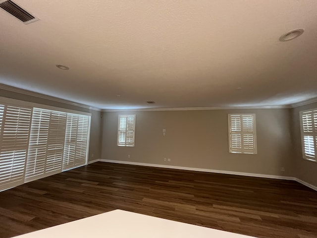 unfurnished room featuring crown molding, wood finished floors, visible vents, and baseboards