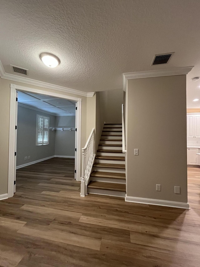 interior space with visible vents, wood finished floors, stairs, and ornamental molding