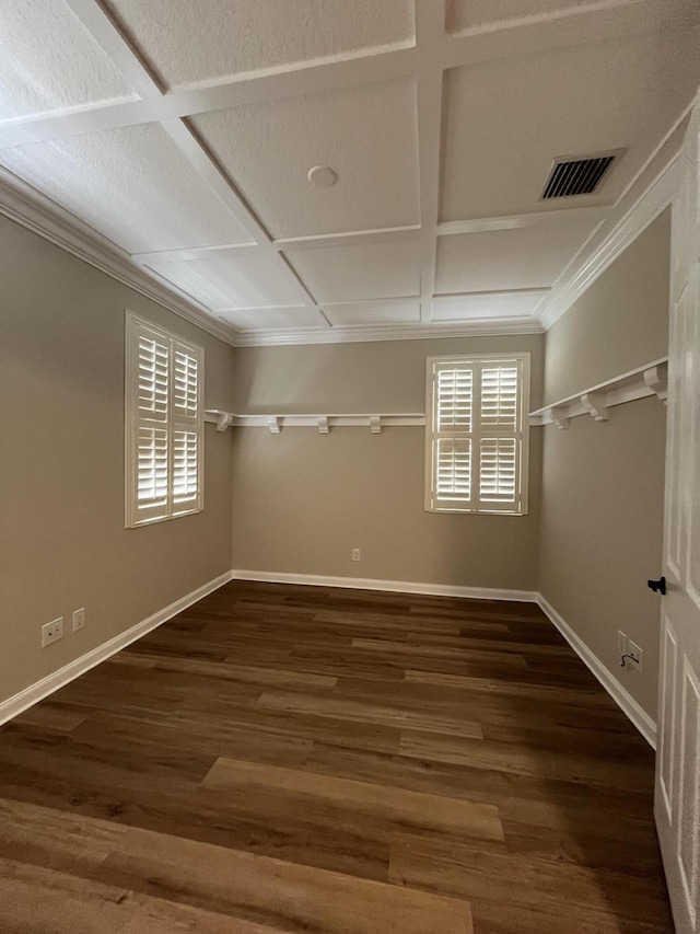 empty room featuring visible vents, baseboards, ornamental molding, wood finished floors, and coffered ceiling