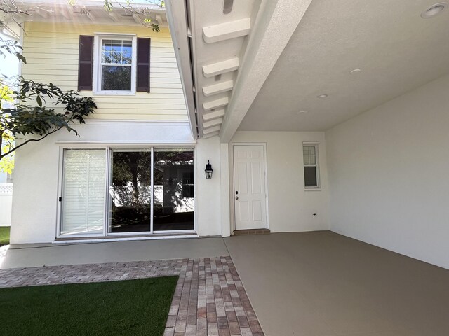 entrance to property with stucco siding and a patio area