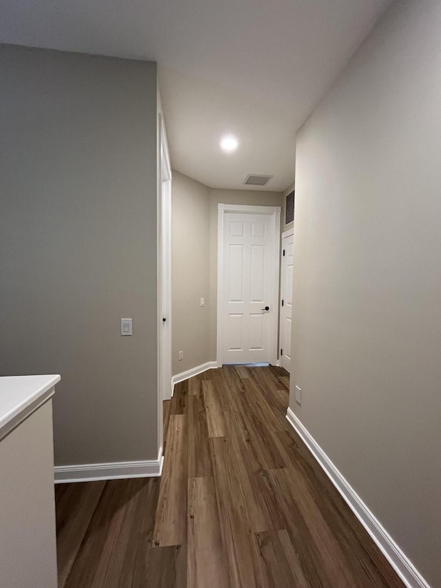 corridor with visible vents, baseboards, and wood finished floors