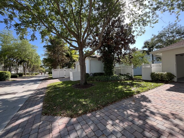 view of home's exterior featuring a gate, stucco siding, a lawn, and fence