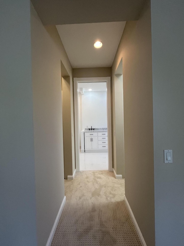 corridor featuring light colored carpet and baseboards