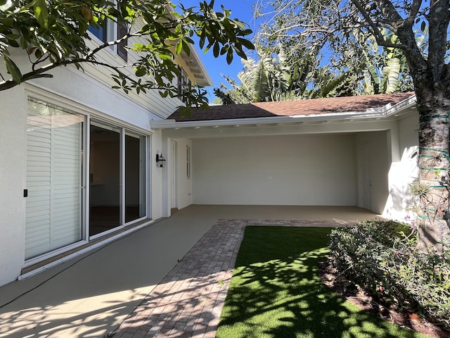 exterior space featuring a shingled roof and stucco siding